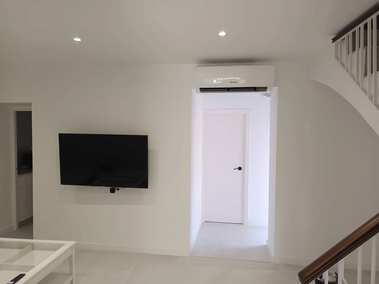 Aire acondicionado instalado sobre la puerta de un salón reformado.