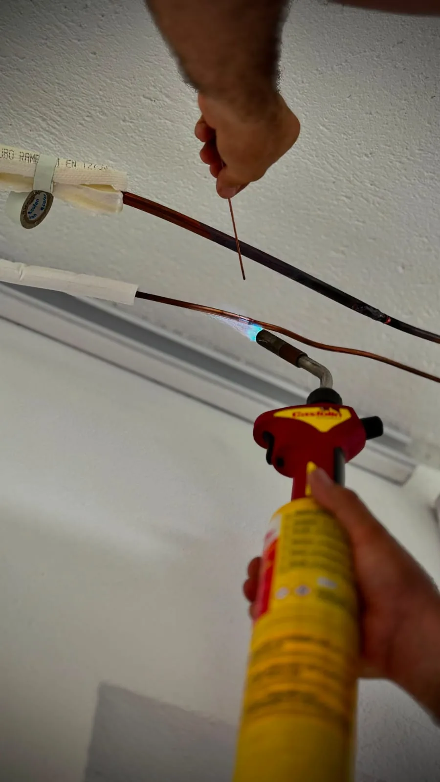 Técnico soldando la tubería de cobre de un aire acondicionado durante la instalación.