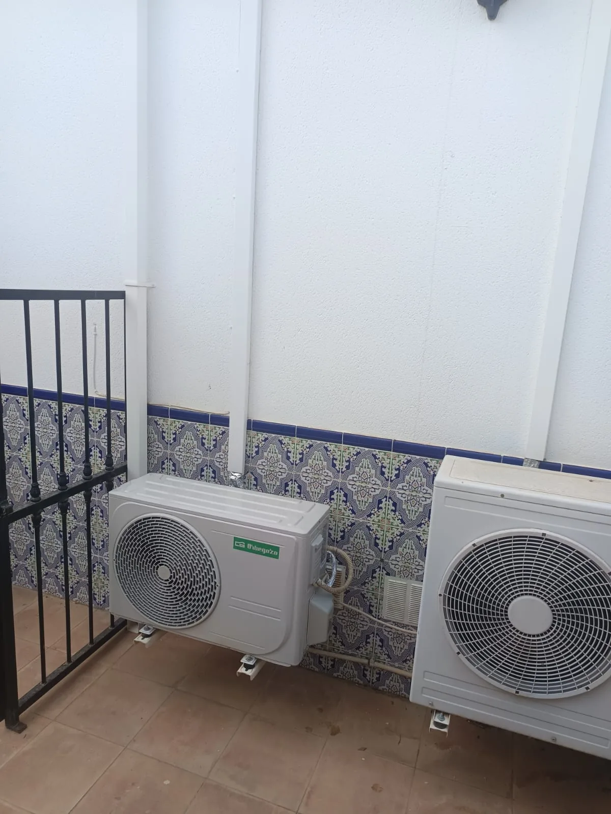 Dos unidades exteriores de aire acondicionado instaladas en un patio alicatado.