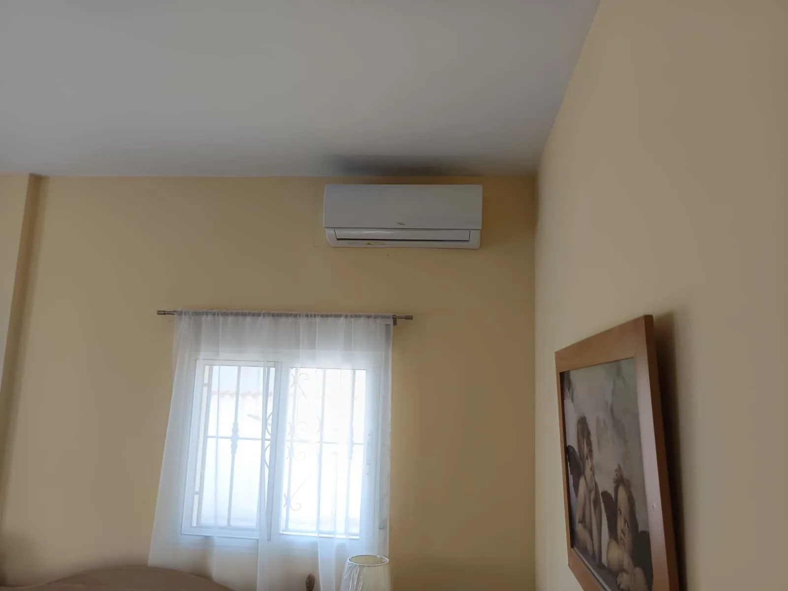 Unidad interior de aire acondicionado instalada sobre la ventana de un salón.