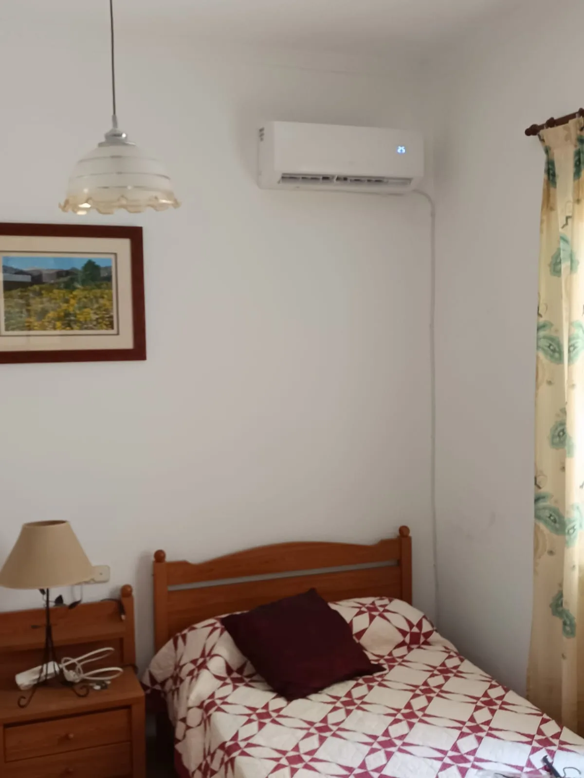 Split de aire acondicionado instalado en un dormitorio, sobre el cabecero de la cama.
