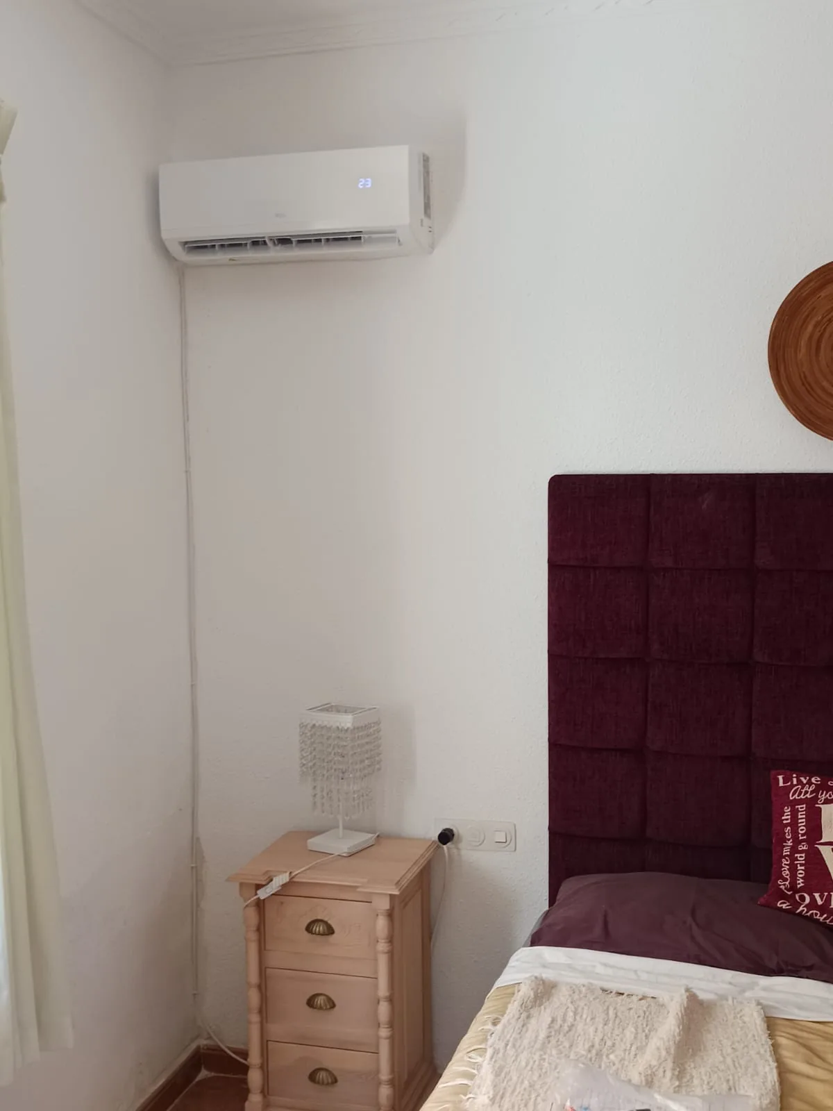 Aire acondicionado instalado en la pared de un dormitorio, junto al cabecero.