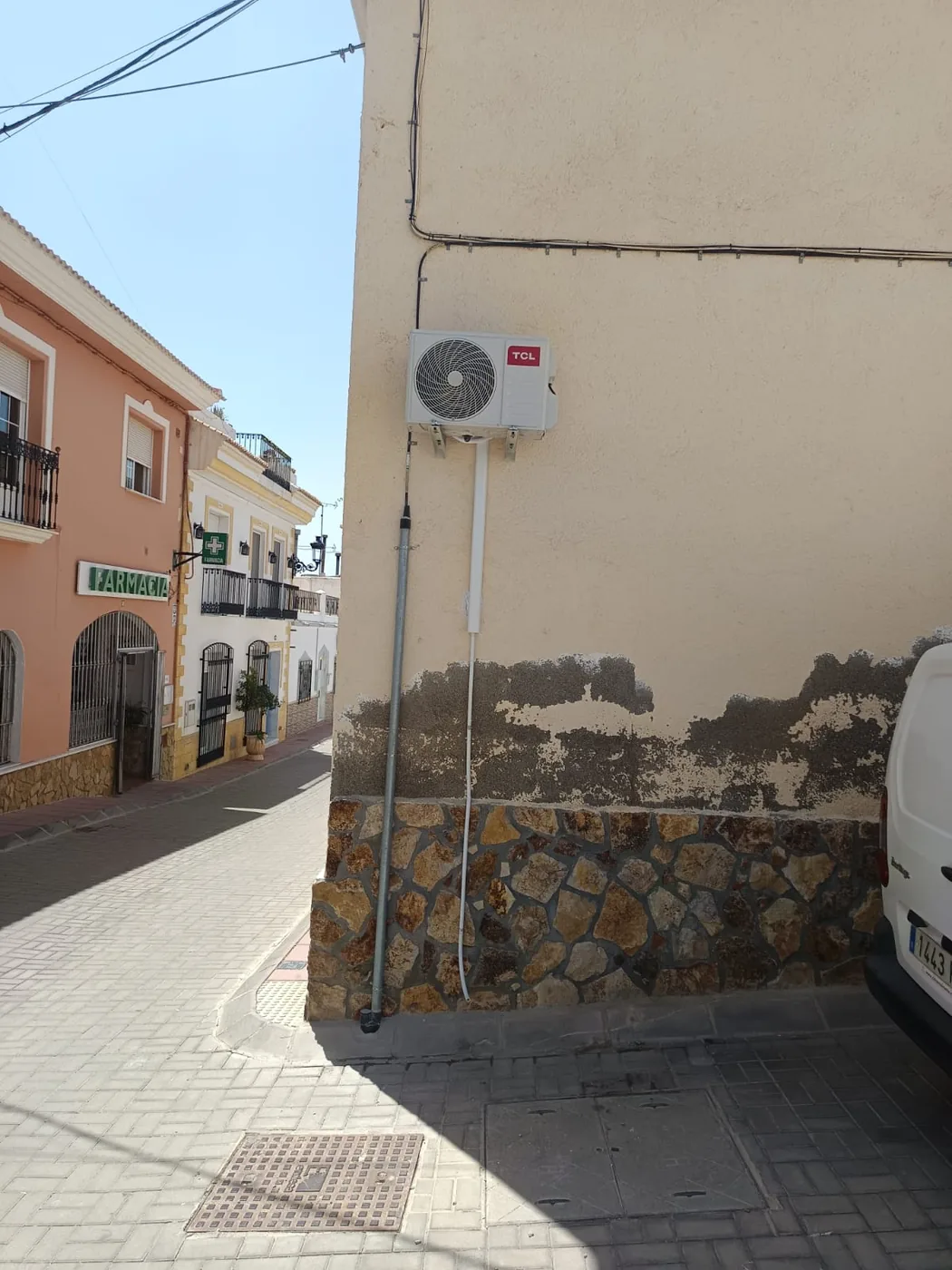 Instalación de aire acondicionado en una calle de pueblo, con la tubería recogida por la fachada.