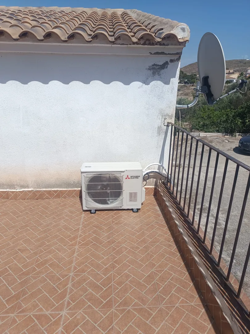 Unidad exterior de aire acondicionado instalada en una azotea, junto a la antena parabólica.