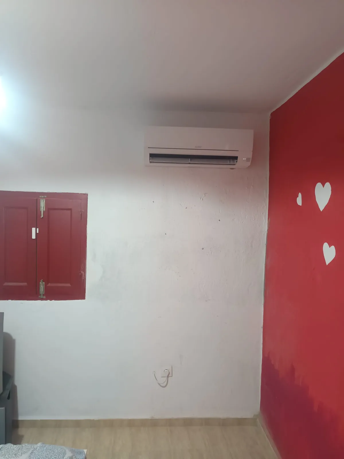 Split de aire acondicionado instalado en un salón de pared roja.
