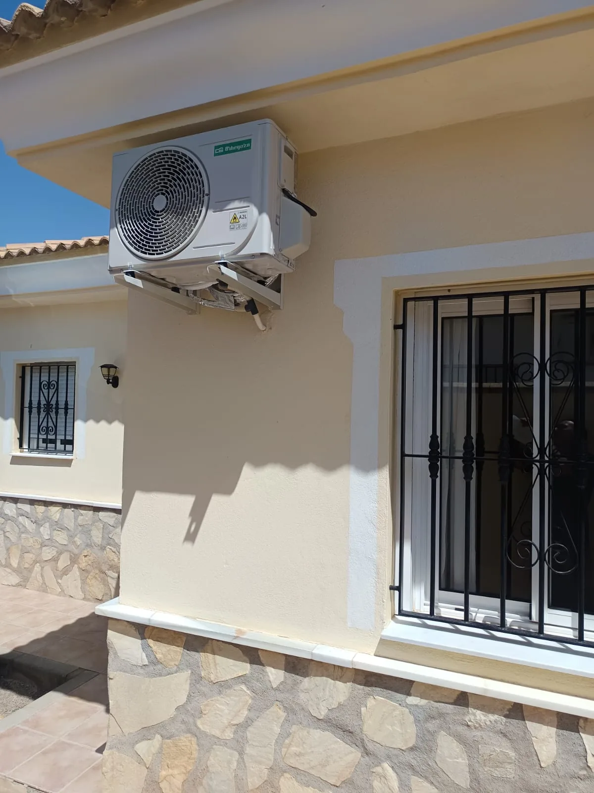 Unidad exterior de aire acondicionado instalada en la fachada de un chalet.