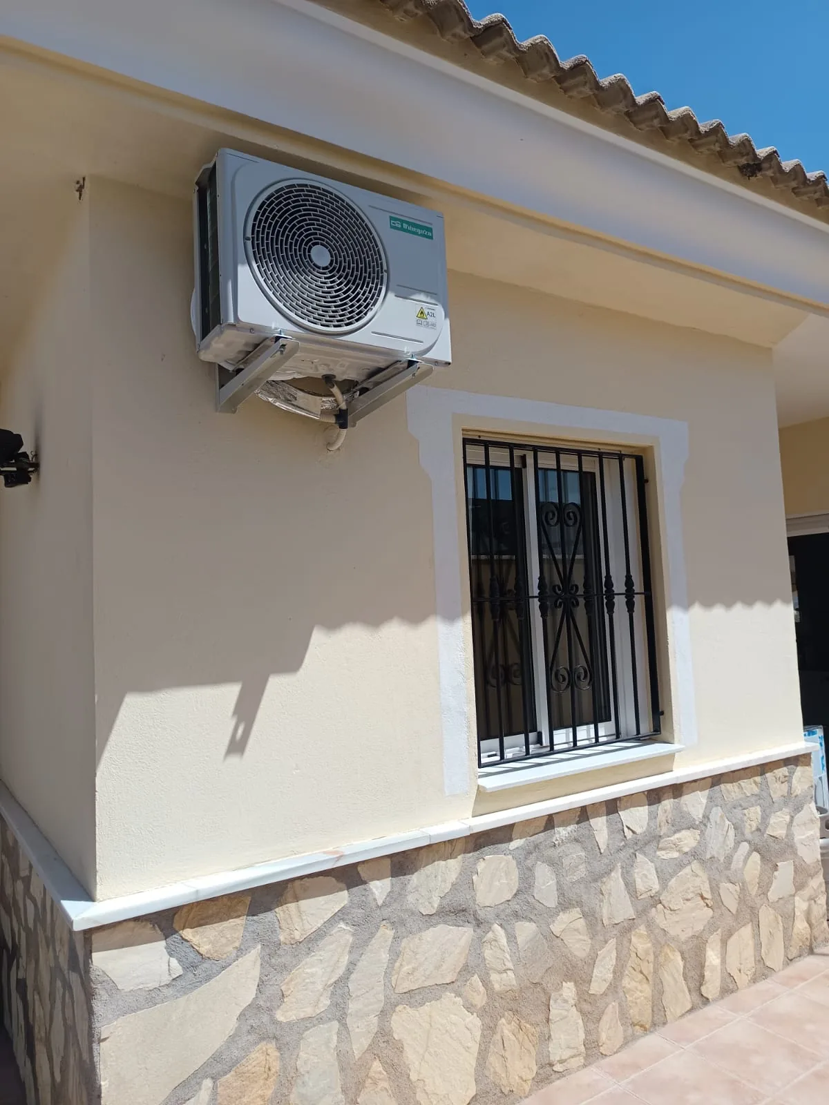 Unidad exterior de aire acondicionado instalada en la esquina de una vivienda.